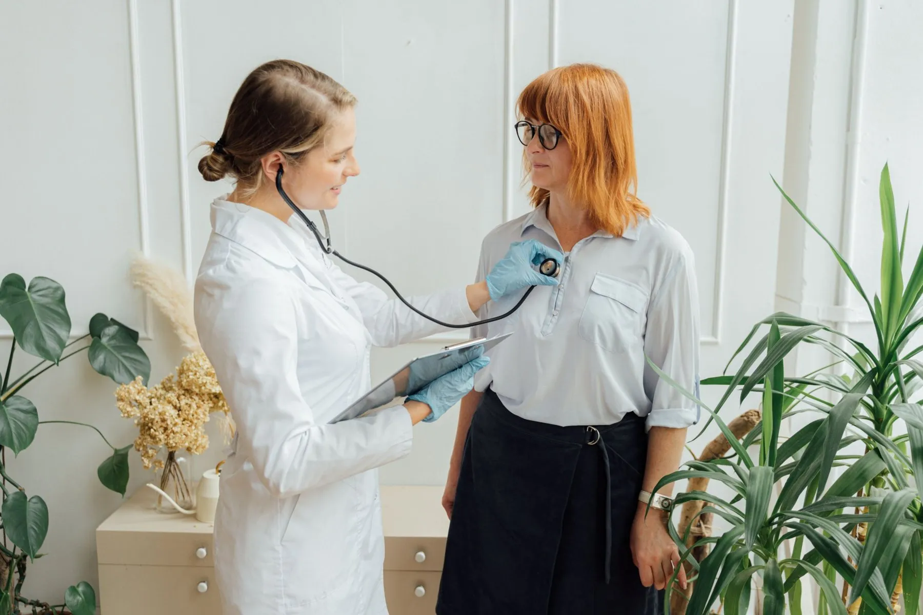 Ärztin hört bei einer Patientin Herz und Lunge mit dem Stethoskop ab